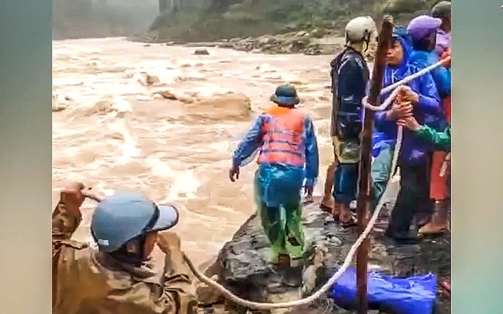 Bốn người dân mắc kẹt trên cồn đất giữa sông khi nước lũ cuồn cuộn - Ảnh 1.