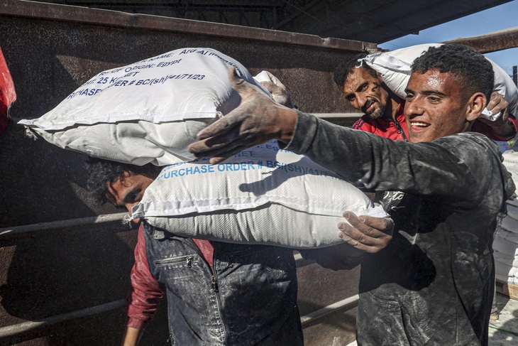 Nhân công dỡ túi đồ viện trợ nhân đạo vào Gaza tại cửa khẩu biên giới Kerem Shalom,  ở Rafah, phía Nam Dải Gaza, ngày 17-2 - Ảnh: AFP