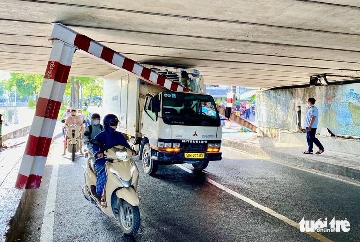 Xe tải “cõng” theo khung giới hạn có chiều cao 2m chui kẹt vào gầm cầu Bông - Ảnh: TIẾN QUỐC