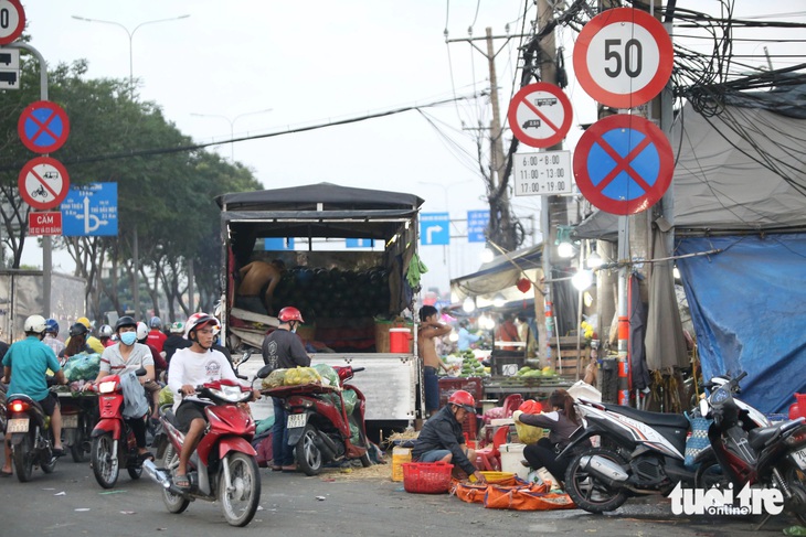 Một xe tải chở dưa hấu đậu trước chợ đầu mối Thủ Đức để xuống hàng hóa, cộng với nhiều xe máy đi ngược chiều, xung đột với dòng xe chạy đúng chiều, khiến giao thông qua khu vực ùn ứ 