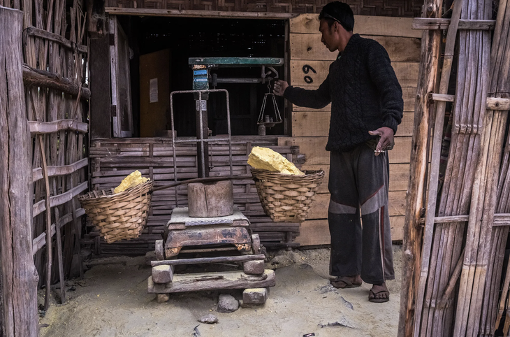 Một thợ mỏ đang cân số lưu huỳnh mà anh kiếm được - Ảnh: BARCROFF IMAGES