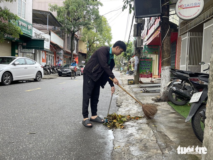 Một số người dân chủ động quét lá rụng trước vỉa hè nhà mình - Ảnh: HOÀNG TÁO