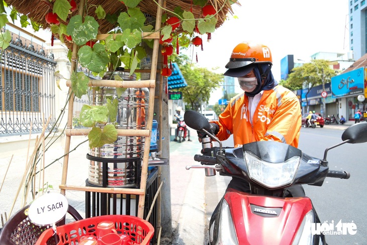 Anh Thiện ghé tiếp thêm nước trước khi chạy đi đón khách. “Thỉnh thoảng buổi trưa nếu chạy gần đây tôi đều ghé lấy nước. Nắng nóng thế này, mấy bình nước lạnh miễn phí là quý lắm“ - anh nói.