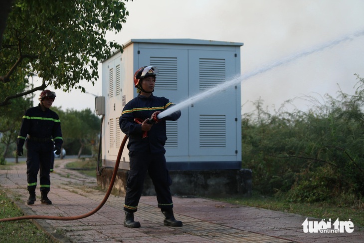 Lực lượng cảnh sát PCCC có mặt phun nước xung quanh tủ điện để tránh lửa bén vào - Ảnh: MINH HÒA