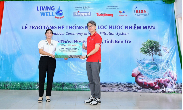 Ông Wong Wai Foo, Giám đốc bộ phận Phát triển Bền vững, Tập đoàn Keppel tại Việt Nam, trao biểu trưng cho Bà Trần Thị Minh Châu, Phó Chủ tịch UBND xã Tân Thuỷ, huyện Ba Tri, tỉnh Bến Tre tại lễ trao tặng hệ thống máy lọc nước nhiễm mặn thuộc dự án Living Well