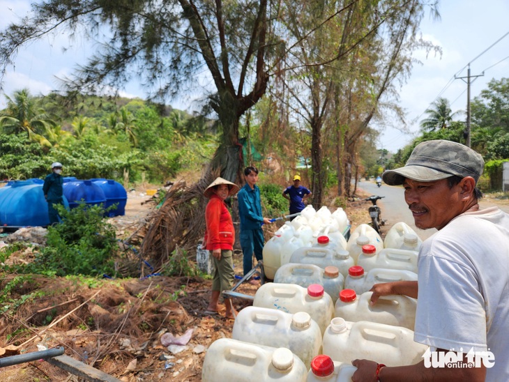 Ông Lâm Văn Hoàng đẩy xe mang 12 can nhựa chờ hứng nước về nhà.