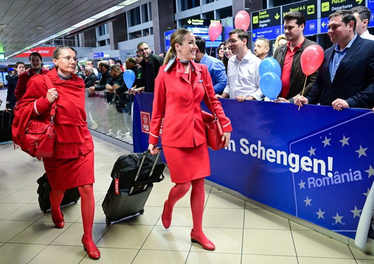 Các tiếp viên hàng không đi bộ cạnh biểu ngữ “Chào mừng đến Schengen!” bằng tiếng Romania tại sân bay quốc tế Henri Coandă hôm 31-3, ngay sau khi Romania chính thức gia nhập một phần khu vực Schengen - Ảnh: AFP