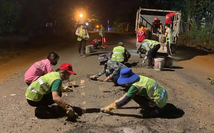 Dưới ánh đèn đường, các bạn trẻ đội tình nguyện vá đường ở phố núi lại cùng nhau làm việc có ích cho đời - Ảnh: TUẤN THÀNH