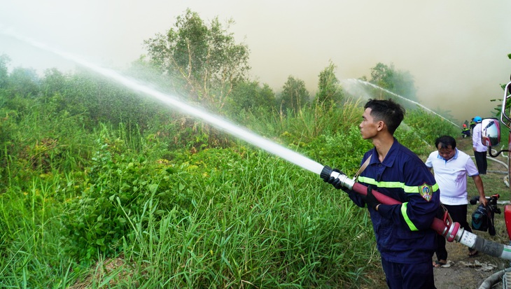 Lực lượng chức năng nỗ lực cắt đường băng để cản lửa - Ảnh: THANH HUYỀN