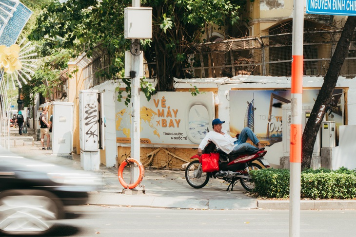 Chú Công, tài xế xe ôm truyền thống, kiếm một bóng râm tại ngã tư đường Nam Kỳ Khởi Nghĩa (quận 3) để tránh nóng - Ảnh: THANH HIỆP