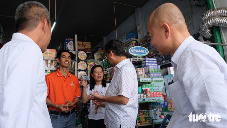 Anh Đỗ Văn Quyền (áo cam) cùng chị Đặng Thị Quỳnh (chủ tiệm tạp hóa Quỳnh Giao, quận 12) chia sẻ về tình hình kinh doanh và kỳ vọng phát triển tốt, khi đại diện lãnh đạo UBND TP.HCM ghé thăm - Ảnh: BÔNG MAI