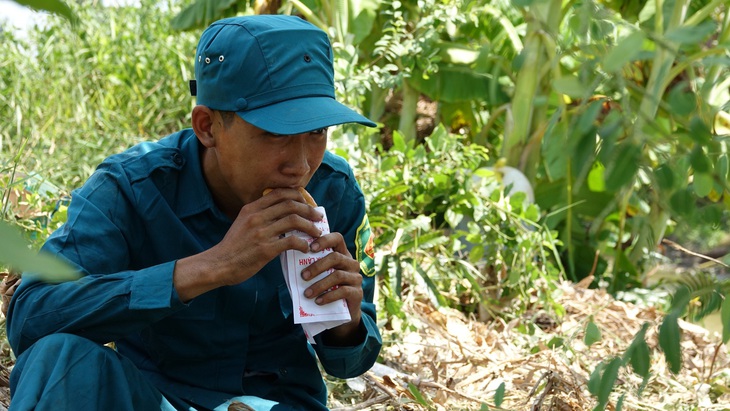 Lực lượng dân quân tự vệ tranh thủ ăn trưa, sau đó tiếp tục hỗ trợ chữa cháy - Ảnh: CHÍ CÔNG