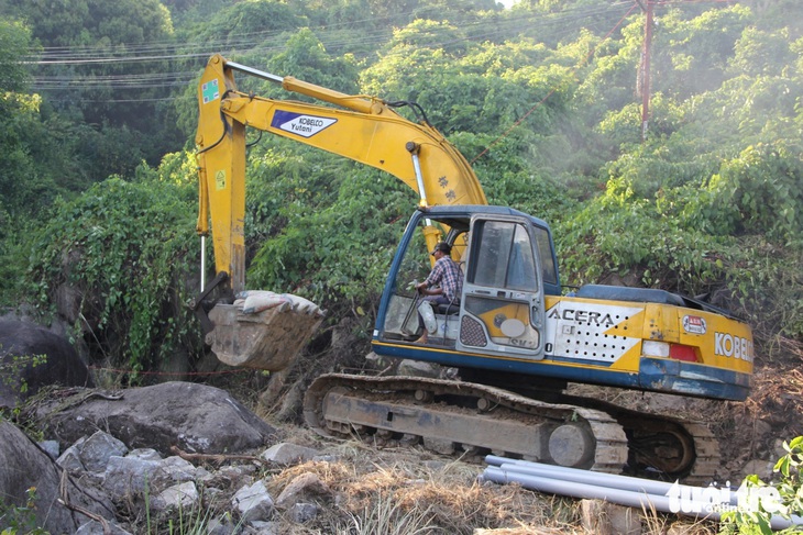 Máy xúc được huy động đến hiện trưởng để vận chuyển xi măng lên sườn núi - Ảnh: NGUYỄN HOÀNG