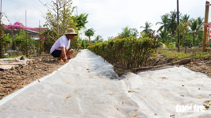 Ông Nguyễn Văn Sự (xã An Minh Bắc, huyện U Minh Thượng) lót lưới, đổ đá, mở đường tạm cho học sinh đi học - Ảnh: CHÍ CÔNG