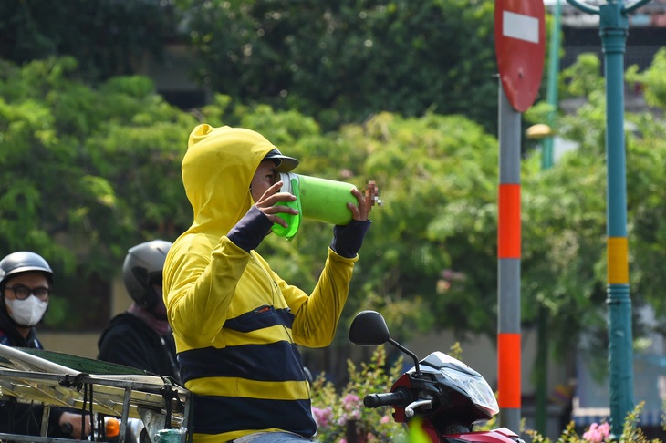 Một người dân tranh thủ uống nước giải nhiệt dưới cái nắng nóng gần 40 độ C (ảnh chụp chiều 8-4 trên đường Lê Văn Sỹ, quận 3, TP.HCM) - Ảnh: TỰ TRUNG