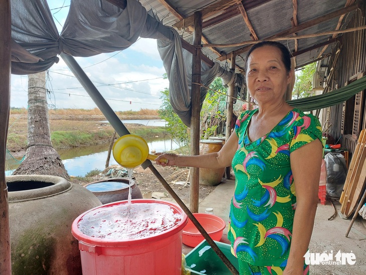 Bà Phan Bích Liên (vợ ông Tý) đã tranh thủ mưa xuống hứng nước để sinh hoạt trong gia đình - Ảnh: CHÍ CÔNG