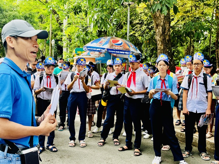 Các em học sinh lắng nghe thông tin từ hướng dẫn viên du lịch để chắt lọc truyền tải vào bài thi - Ảnh: MỸ DUNG