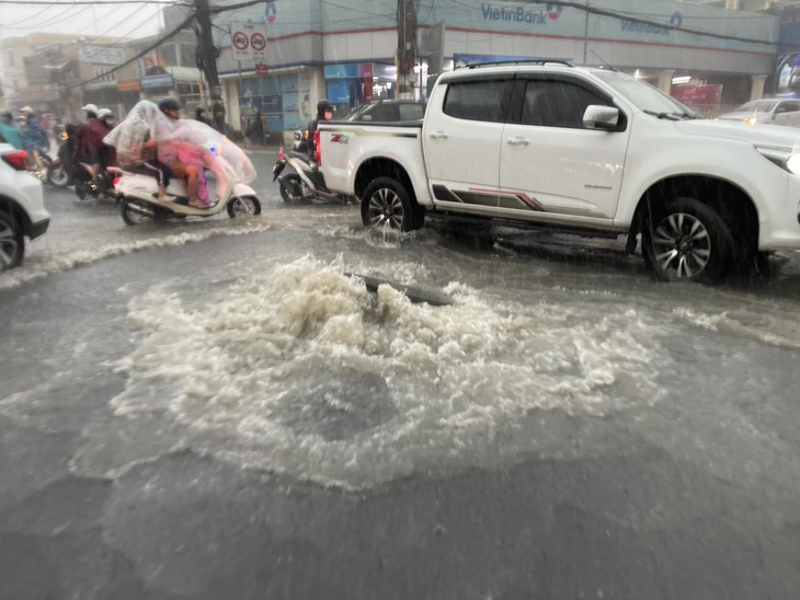 Ngay vòng xoay trước chợ Thủ Đức, một mảng đường lớn gần hố ga bị sụt lún hở hàm ếch. Cạnh đó chừng 5m, một hố ga khác đang bung lên, nước phun xối xả - Ảnh: LÊ PHAN