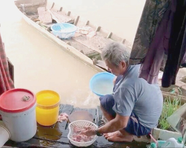 Ông Trần làm sạch đầu cá ba sa trước khi chế biến - Ảnh cắt từ màn hình