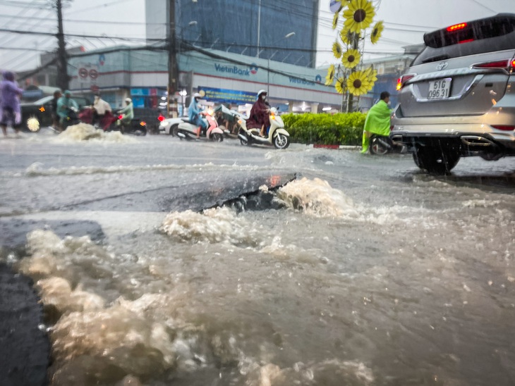 Các mảng nhựa đường bị bong tróc trong cơn mưa chiều 15-5 ở khu vực chợ Thủ Đức - Ảnh: LÊ PHAN