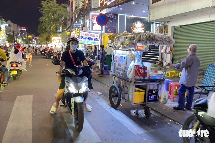 Người mua hàng đi ngược chiều, đậu ngay lòng đường để mua hàng tại các xe đẩy hàng rong gây cản trở giao thông - Ảnh: TIẾN QUỐC 