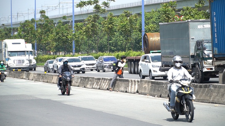 Nam sinh vừa nghe điện thoại vừa băng qua xa lộ Hà Nội, TP Thủ Đức - Ảnh: XUÂN ĐOÀN