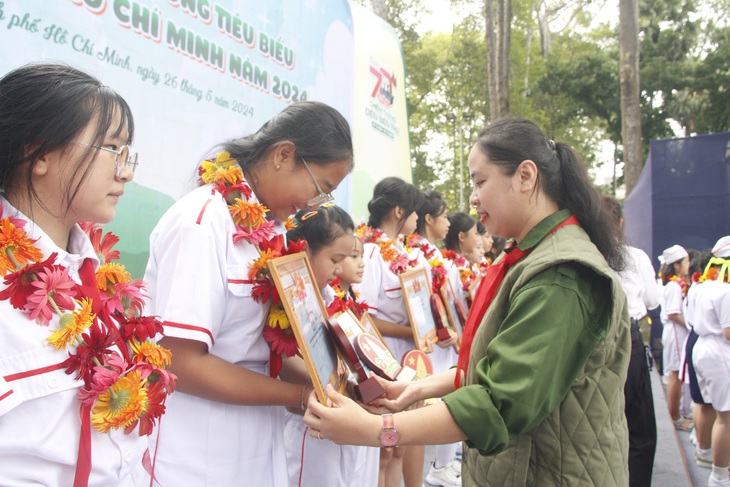 Chị Trịnh Thị Hiền Trân - phó bí thư Thành Đoàn, chủ tịch Hội đồng Đội TP.HCM - trao bằng khen cho các liên đội trưởng tiêu biểu cấp thành - Ảnh: CÔNG TRIỆU