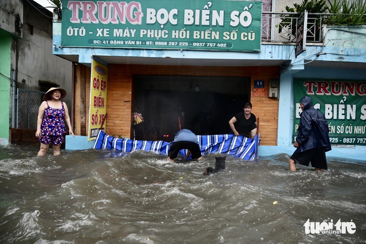 Người dân căng bạc, liên tục tát nước trên đường Đặng Văn Bi - Ảnh: PHƯƠNG QUYÊN