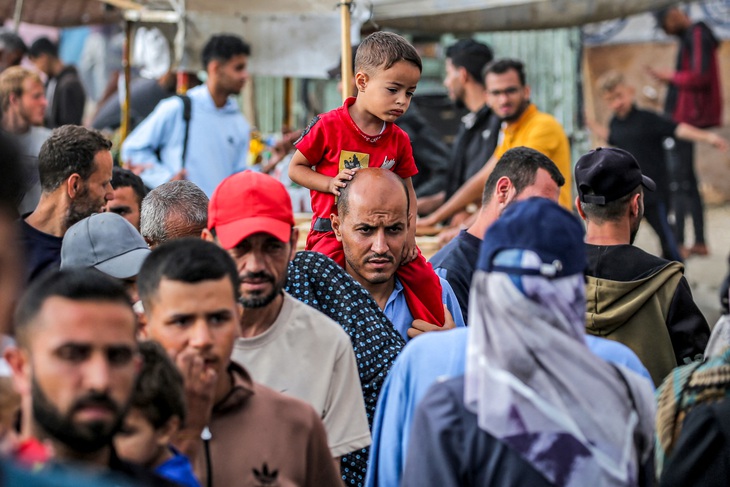 Một người đàn ông cõng con trai trên vai giữa dòng người Palestine tại các lều tạm trú ở TP Rafah tại Dải Gaza hôm 30-4 - Ảnh: AFP