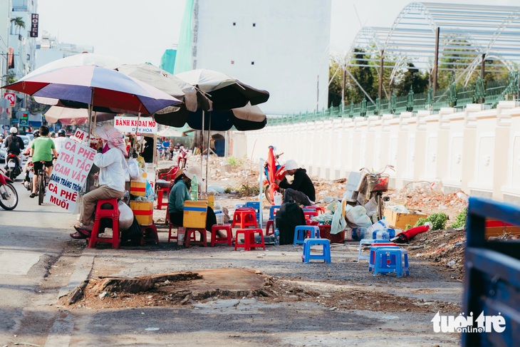 Một xe bán nước giải khát trên lề đường, sát một gốc cây lớn vừa bị đốn hạ - Ảnh: THANH HIỆP