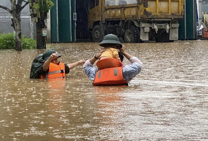 Lực lượng cứu hộ cứu nạn đưa một em bé ra khỏi khu vực ngập sâu ở TP Hà Giang sáng 10-6 - Ảnh: THU PHƯƠNG