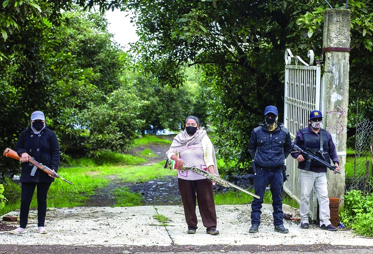 Thành viên Pueblos Unidos canh gác một đồn điền bơ ở Ario de Rosales (Michoacán, Mexico) tháng 7-2021. Ảnh: AFP