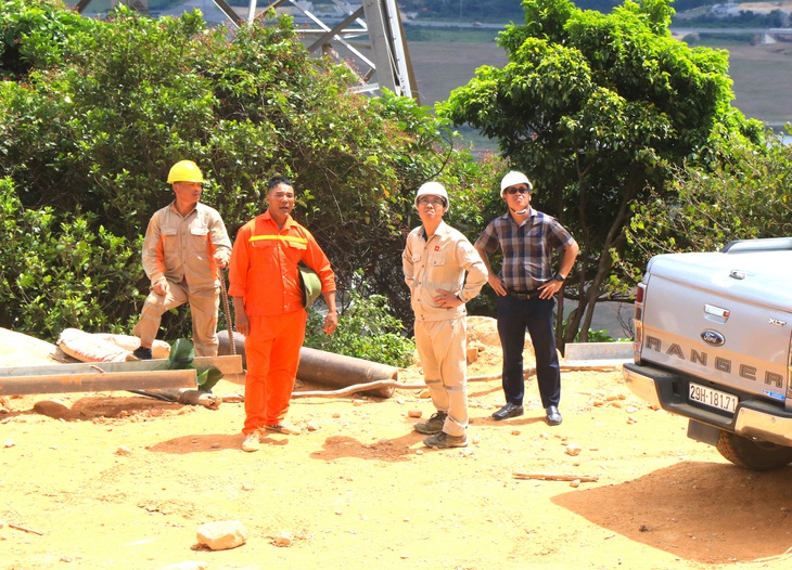 Ông Nguyễn Thành Trung (thứ nhất bên phải) và ông Ưng Vũ Thanh (thứ 2 từ phải sang) chỉ đạo, giám sát thi công dựng cột - Ảnh: LÊ MINH