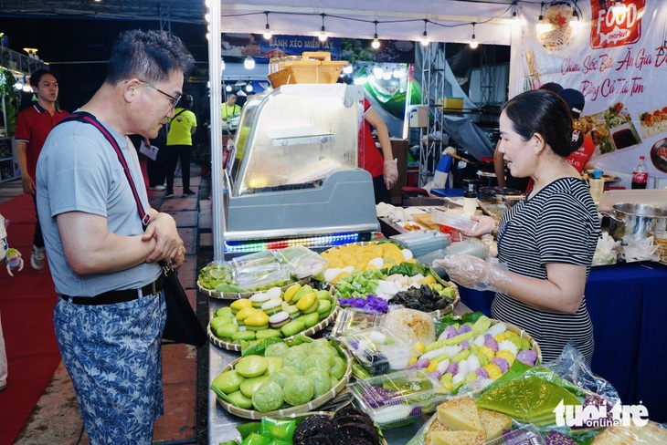 Ông Hishiro (du khách Nhật) đang chọn những loại bánh dân gian của Việt Nam để thưởng thức - Ảnh: THANH HIỆP