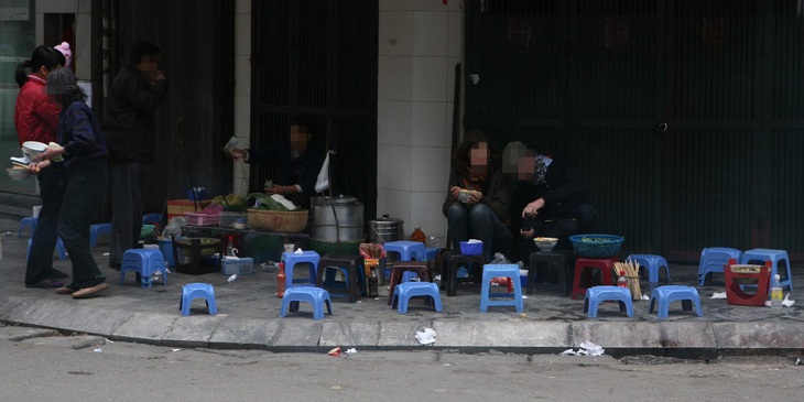 Một hàng ăn bày bán, để vật dụng ăn uống như ống đũa, chai tương ớt dưới lề đường - Ảnh: QUÂN NAM