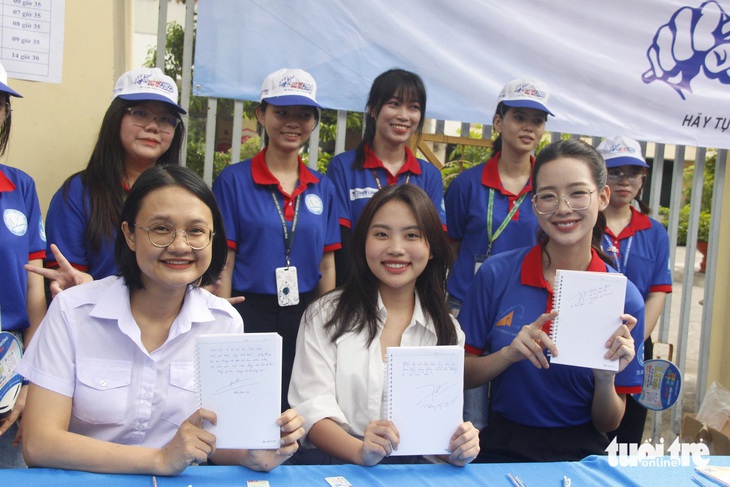 Chị Trần Thu Hà, phó bí thư Thành Đoàn TP.HCM, ca sĩ Phương Mỹ Chi và hoa hậu Lê Nguyễn Bảo Ngọc (hàng đầu, từ trái sang) viết lời chúc gửi đến các sĩ tử - Ảnh: CÔNG TRIỆU