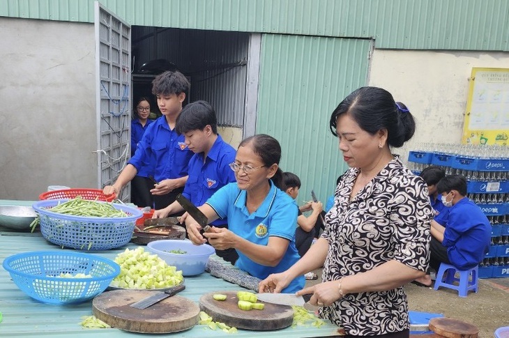 Hơn 20 người gồm giáo viên, phụ huynh và học sinh của trường cùng phụ nấu ăn từ lúc tờ mờ sáng - Ảnh: N.P.