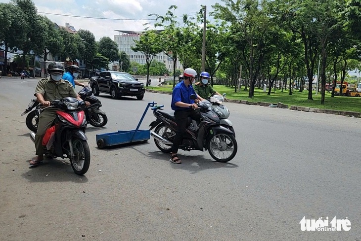 Đoàn thanh niên phường Trung Mỹ Tây (quận 12) phối hợp với công an phường hút đinh trên quốc lộ 1, đoạn từ cầu vượt Quang Trung đến cầu vượt An Sương - Ảnh: NGỌC KHẢI