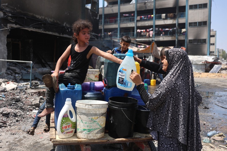 Một bé gái Palestine ngồi trên chiếc xe chất đầy thùng dùng chứa nước tại một trường học trưng dụng làm trại tị nạn ở Jabalia, phía bắc Dải Gaza, ngày 3-6 - Ảnh: AFP