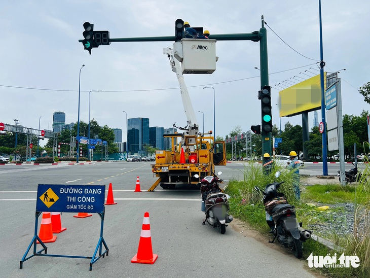 Nhân viên Công ty Chiếu sáng công cộng TP.HCM điều chỉnh đèn tại giao lộ Tố Hữu - Mai Chí Thọ - Ảnh: XUÂN ĐOÀN