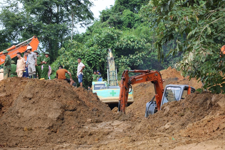 Lực lượng chức năng huy động nhiều máy móc, nhân lực san gạt khối lượng đất đá tràn xuống mặt đường để tạm thông tuyến quốc lộ 34 - Ảnh: ĐỨC MẠNH