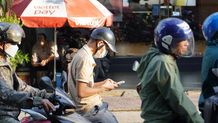 Người đàn ông dùng điện thoại khi chờ đèn ở đường Lý Thường Kiệt, TP Dĩ An,  Bình Dương - Ảnh: ĐỊNH DƯƠNG