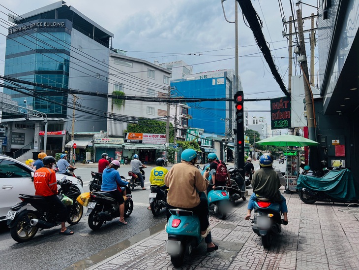 Nhiều người chạy xe lên vỉa hè tìm cách rẽ phải khi đèn đỏ - Ảnh: XUÂN ĐOÀN