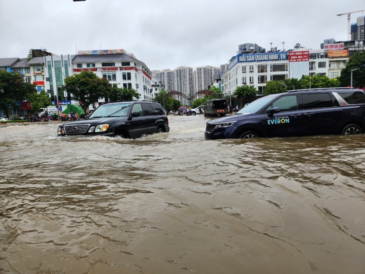 Nhiều ô tô cố "lội" qua đoạn đường ngập nước trước cổng khu A khu đô thị Geleximco Lê Trọng Tấn - Ảnh: B.NGỌC