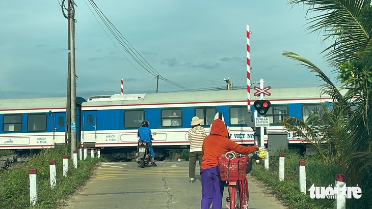 Tàu khách SE19 qua đường ngang nhưng chắn tự động nâng lên khiến nhiều người đi đường sởn gai ốc - Ảnh: HOÀNG TÁO