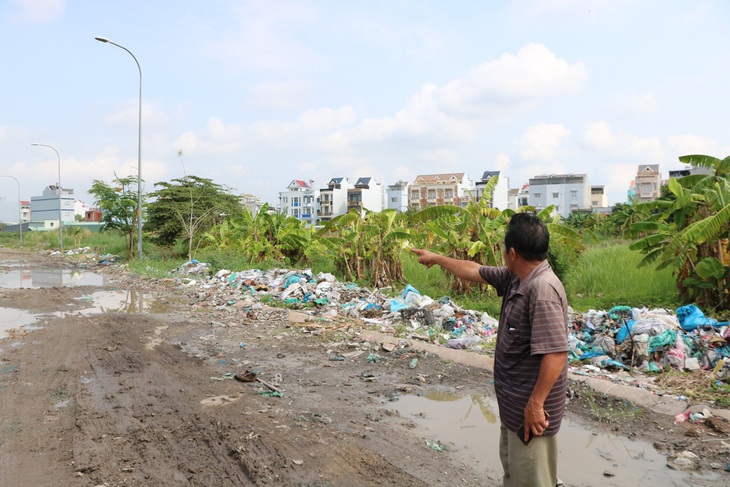 Người dân ngán ngẩm nhìn về khu vực quy hoạch công viên cỏ mọc cao hơn đầu người, đường ngập nước và rác - Ảnh: CẨM NƯƠNG 