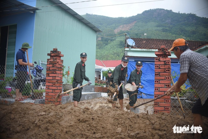 Lực lượng công an, quân đội phụ giúp người dân sống dưới chân núi Cấm dọn dẹp bùn đất tràn vào nhà sau vụ sạt lở núi vào tháng 11-2021 - Ảnh: LÂM THIÊN