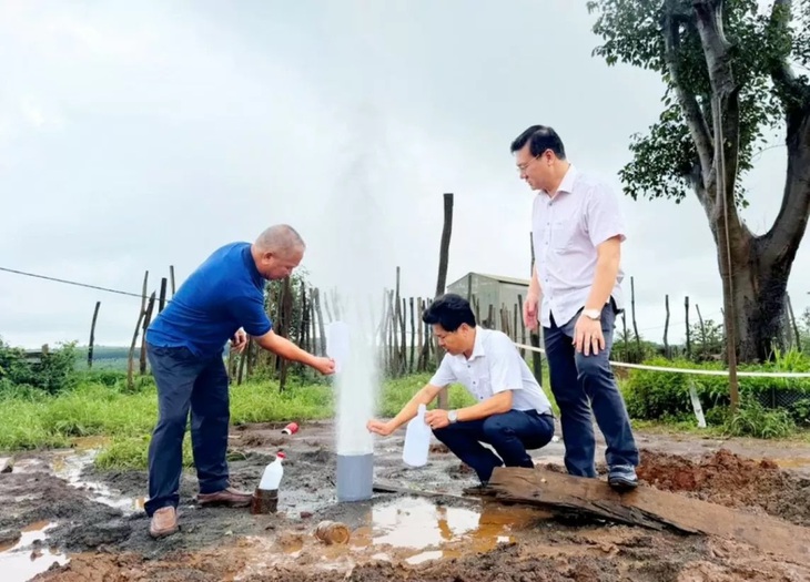 Chuyên gia lấy mẫu nước tại giếng khoan có hiện tượng phun nước mạnh ở Gia Lai ngày 1-8 - Ảnh: H.N. 