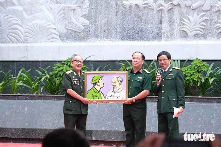 Họa sĩ, Anh hùng Lực lượng vũ trang nhân dân Lê Duy Ứng - nguyên cán bộ công tác tại Bảo tàng Lịch sử quân sự Việt Nam - trao tặng bức tranh Bác Hồ với chiến sĩ giải phóng quân - Ảnh: HÀ THANH