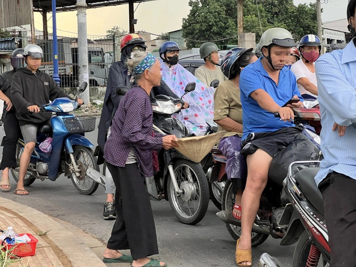 Một phụ nữ lớn tuổi xin tiền ở ngã ba cổng Khu công nghệ cao, TP Thủ Đức - Ảnh: XUÂN ĐOÀN